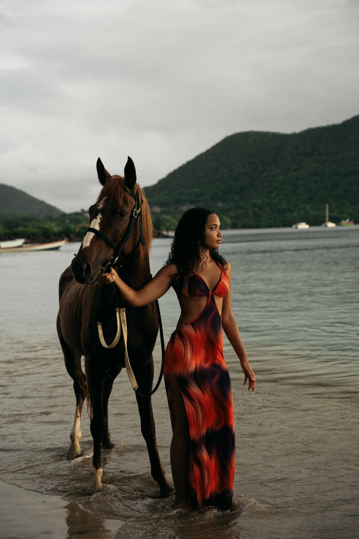 A woman walking with a horse on a beach